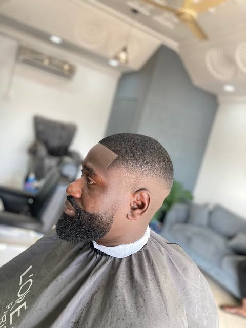 A barber focused on cutting a client's hair in a modern barbershop