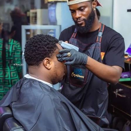 Barber shaping a fade with clippers inside a modern barbershop